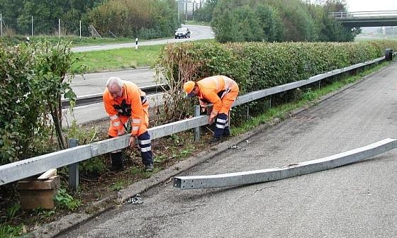 Eine defekte Leitschranke, die von zwei TBA-Mitarbeitenden ersetzt wird.