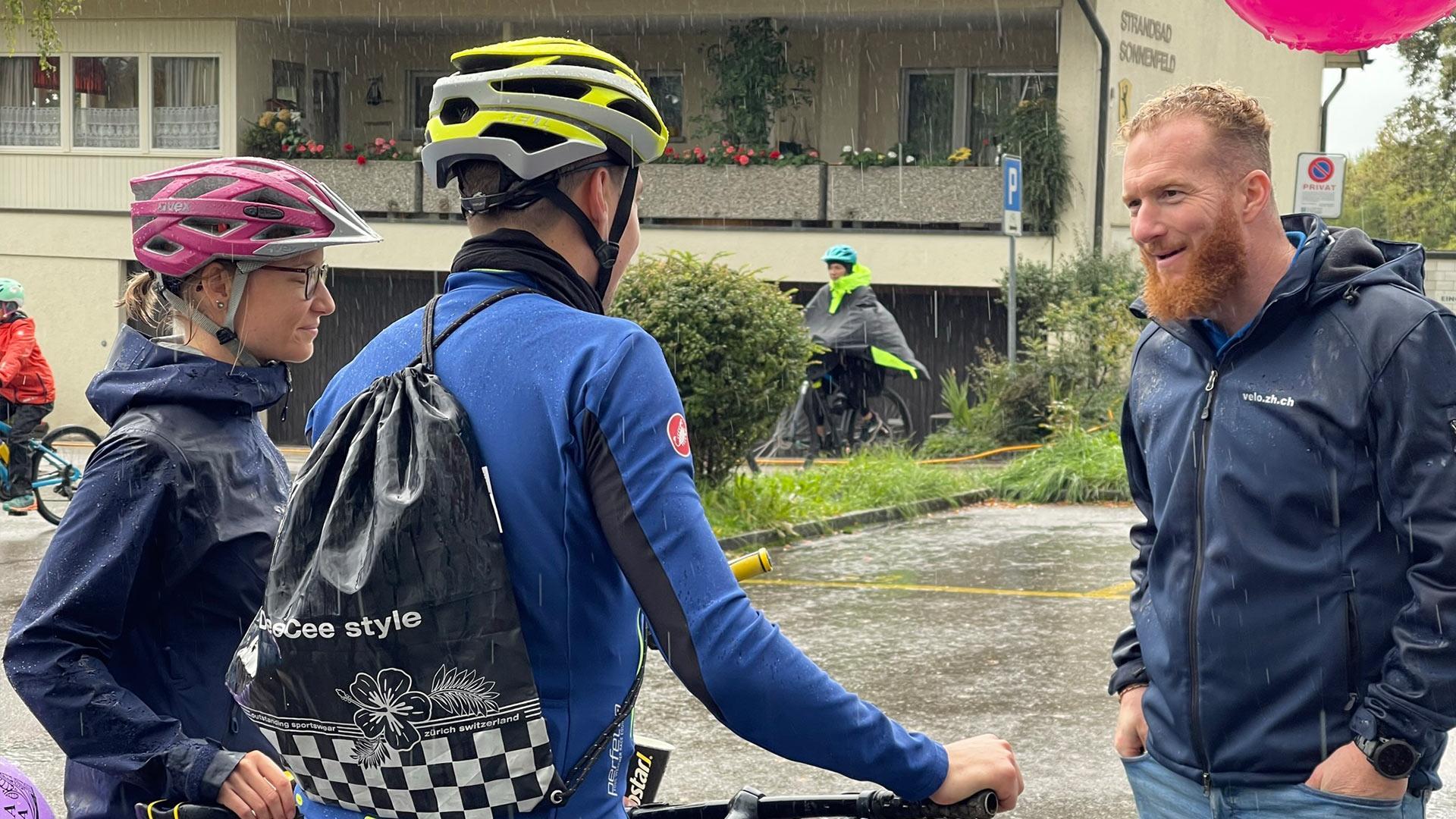 Selbst strömender Regen kann die gute Stimmung am Anlass nicht trüben. Unser Fachstellenleiter spricht mit Velofahrenden, die unseren SlowUp-Stand besuchten.